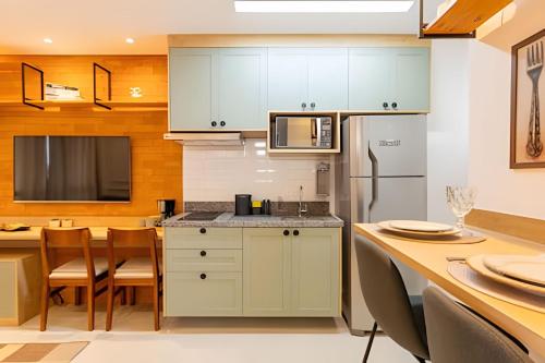 a kitchen with white cabinets and a table with chairs at Today Perdizes in Sao Paulo