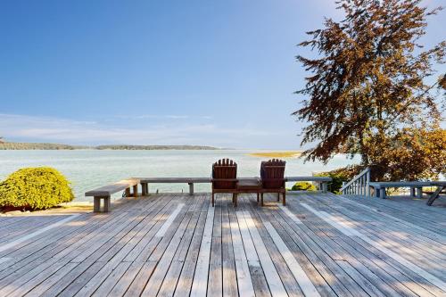 two benches sitting on a wooden deck overlooking the water at Mintercreek Cabin in Gig Harbor