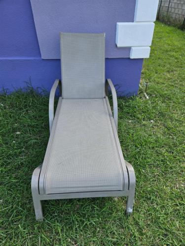 a metal chair sitting in the grass next to a building at Sunrise Haven Holiday Apartments Barbados in Christ Church