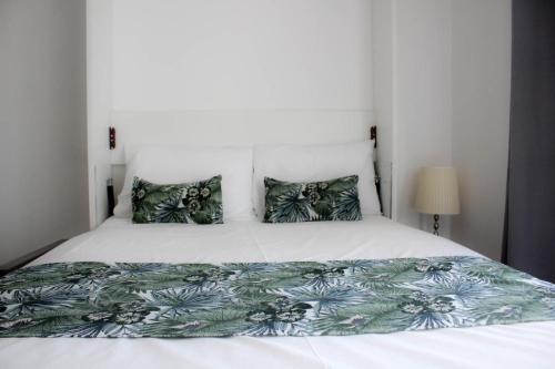 ein Schlafzimmer mit einem großen weißen Bett und grünen Kissen in der Unterkunft stuDio 57 II in Alexandroupoli