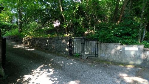 a stone fence with a gate in front of trees at Robin Hill Cottage in Amesbury