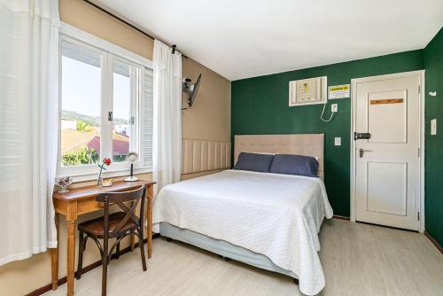 Un dormitorio con una cama y un escritorio y una ventana. en Guesthouse, en Florianópolis