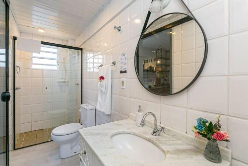 Un baño con lavabo, inodoro y espejo. en Guesthouse, en Florianópolis