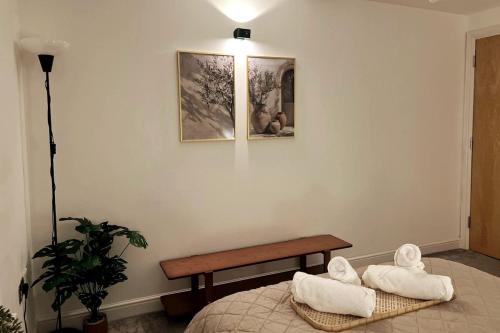 a room with a bench and towels on a bed at Cosy 1-Bed Apartment near Hertfordshire Uni & Hatfield Business Park in Hatfield