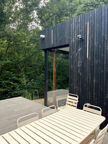 a wooden table and chairs and a black building at Serenity Lodge Durbuy - Sauna & Jacuzzi in Durbuy