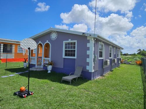 a purple house with a chair in a yard at Sunrise Haven Holiday Apartments Barbados in Christ Church