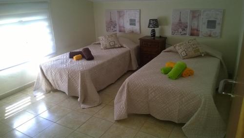 two twin beds in a bedroom with white sheets at Apartamento Teixeira 2 in Arco da Calheta