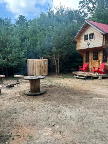 a picnic table in front of a log cabin at Forest Bunkie Trails & Stargazing in Simcoe