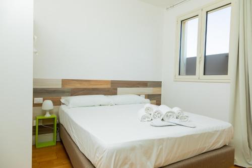 a bedroom with a white bed with shoes on it at Boomerang Village in Torre Colimena