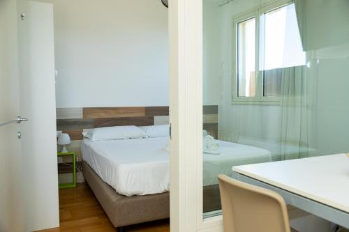 a bedroom with a bed and a table and a window at Boomerang Village in Torre Colimena