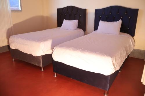 two beds in a room with white sheets and pillows at Casa Cóndor Ausangate in Tinke