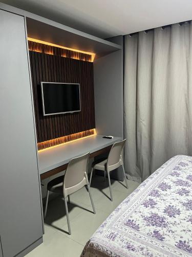 a bedroom with a desk with two chairs and a tv at Get One - João Pessoa in João Pessoa
