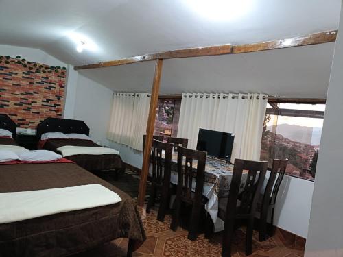 a room with two beds and a tv and a table at 7 Borreguitos GUESTHOUSE in Cusco