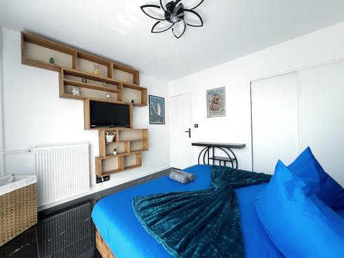 a bedroom with a blue bed and a flat screen tv at Delrio in Nantes