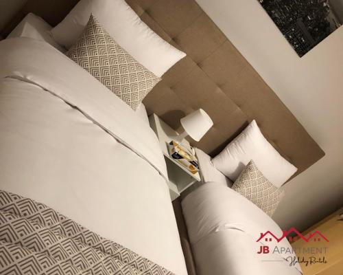 a bedroom with a bed with white sheets and pillows at JB Apartment -B18- in Kenitra