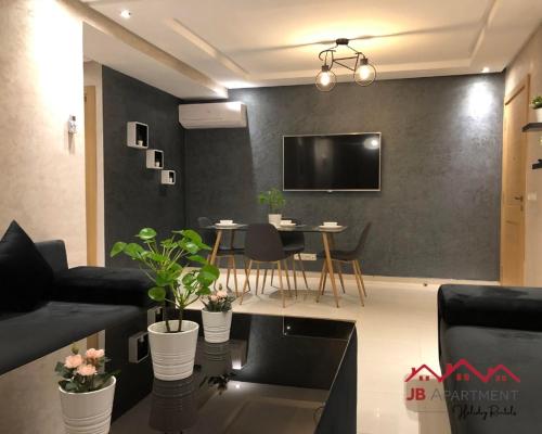 a living room with a table and a tv on a wall at JB Apartment -B18- in Kenitra