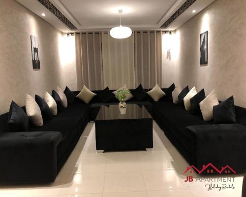 a living room with black couches and a table at JB Apartment -B18- in Kenitra