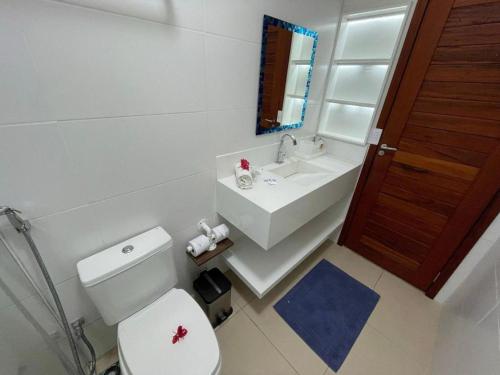 a bathroom with a white toilet and a sink at Reserva BG - Apto Peixe Boi - Frente mar in Barra Grande