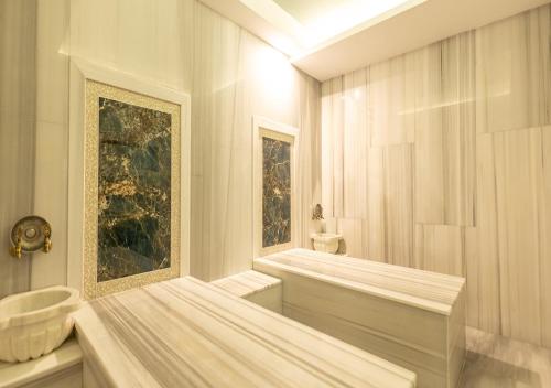 a white bathroom with a tub and a sink at Peramis Hotel & Spa in Antalya