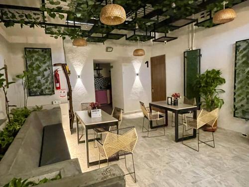 a room with two tables and chairs and potted plants at Nómada22 -Hostal moderno en el centro de Neiva in Neiva