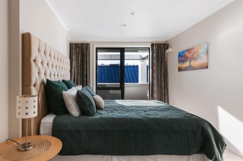 une chambre avec un lit vert et une fenêtre dans l'établissement Cosy Mount Base King Bed Ensuite & Top Location, à Mount Maunganui