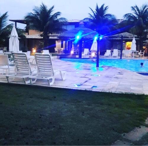 a group of lawn chairs next to a pool at night at Geribá Beach Apart Hotel casa 504 in Búzios