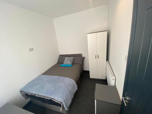 a small bedroom with a bed and a cabinet at Rossy Guest House in Stoke on Trent