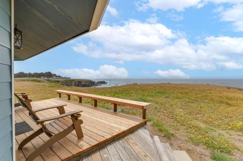 a wooden deck with a bench and a view of the ocean at Walk to Beach Luxury Oceanfront Escape in Caspar in Caspar