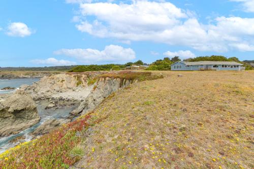 a house on top of a cliff next to the water at Walk to Beach Luxury Oceanfront Escape in Caspar in Caspar