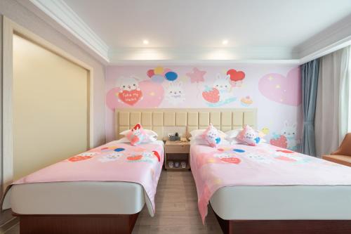 two beds in a room with hello kitty wallpaper at Rezen Select Shanghai International Resort in Shanghai