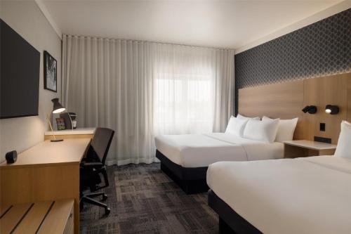 a hotel room with two beds and a desk at Best Western Plus City Centre Centre-Ville in Quebec City