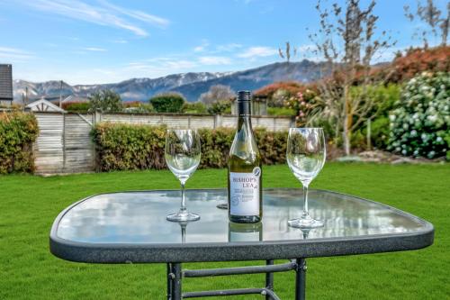 a bottle of wine and two glasses on a table at Hanmer Apartments in Hanmer Springs