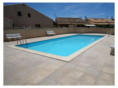 une grande piscine bleue entourée de deux bancs dans l'établissement Maison de vacances Kurt dans le sud de la France, à Portiragnes