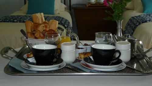 a tray with two cups of coffee and a tray of bread at Domaine de Janis & Spa in Le Vigan