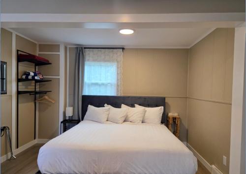 a bedroom with a bed with white sheets and a window at Lido Motel in Radium Hot Springs