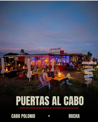 a group of people sitting at tables in front of a building at Puertas al Cabo in Cabo Polonio