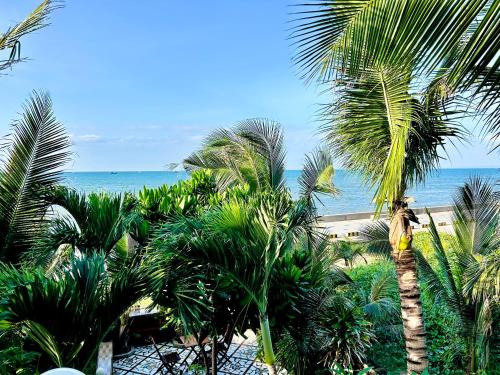 a view of the ocean from a resort with palm trees at Sầm Sơn Boutique Hotel Phan Thiết in Phan Thiet