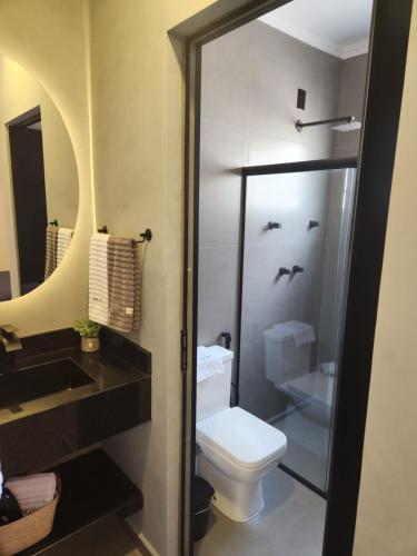 a bathroom with a toilet and a sink and a mirror at ANGATU CHALÉS Bem Estar, Aconchego e Conforto in Serra Negra