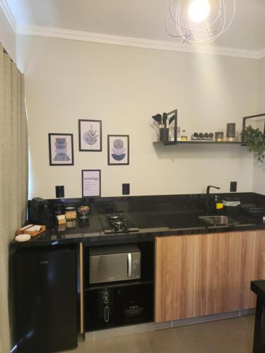 a kitchen with a black counter top and a microwave at ANGATU CHALÉS Bem Estar, Aconchego e Conforto in Serra Negra