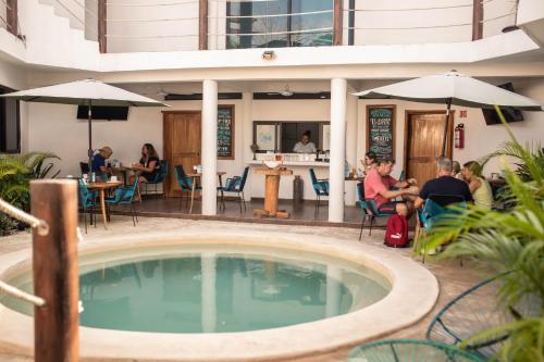 a group of people sitting around a swimming pool at Ade Hotel Bacalar in Bacalar
