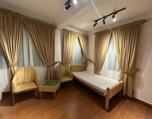 a bedroom with a bed and two chairs and windows at Bhurban Suites in Murree
