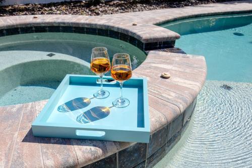 two glasses of wine on a table next to a swimming pool at NEW! Palm Harbor Hideaway - Beautiful, Spacious 4BR Home with Amazing Pool in Palm Harbor