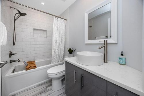 a white bathroom with a sink and a toilet at NEW! Palm Harbor Hideaway - Beautiful, Spacious 4BR Home with Amazing Pool in Palm Harbor