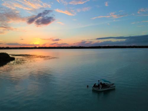 a boat on a lake with a sunset at Ade Hotel Bacalar in Bacalar