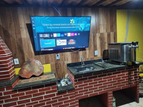 a tv on a brick wall with a sink at Pousada Flor do Caribe in Rio das Ostras