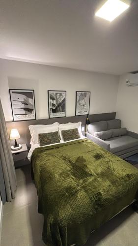 a bedroom with a large green bed and a couch at GO Rio Branco by LikeHome in Porto Alegre