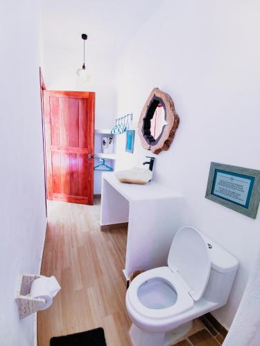 a bathroom with a white toilet and a mirror at Ade Hotel Bacalar in Bacalar