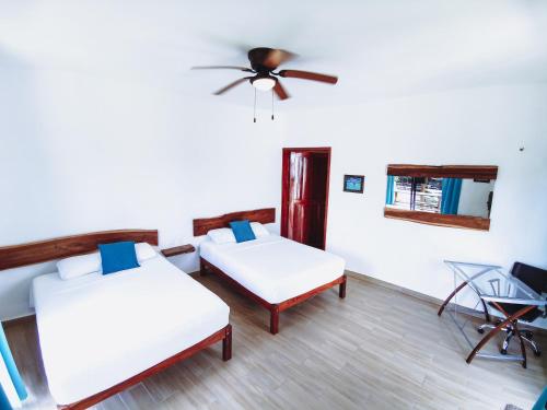 a room with two beds and a ceiling fan at Ade Hotel Bacalar in Bacalar