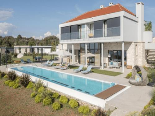uma casa com uma piscina na frente em Grandiose Brac Villa Villa Mediteranea 6 Bedrooms Infinity Pool & Outdoor Tv em Škrip
