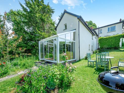 Un jardín con un invernadero con mesa y sillas. en Tan Y Castell Cottage - Llanmill, en Lampeter-Velfrey